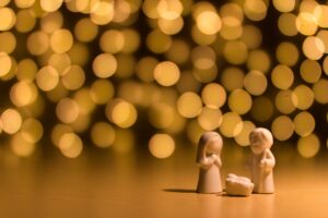 Small nativity figures with Christmas lights in the background