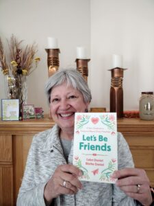 The author holding a copy of "Let's Be Friends!" 
